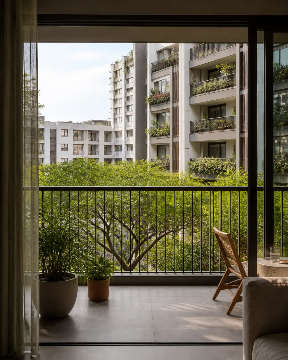 A shaded condominium balcony looking out over a dense mid rise neighbourhood and mature trees.