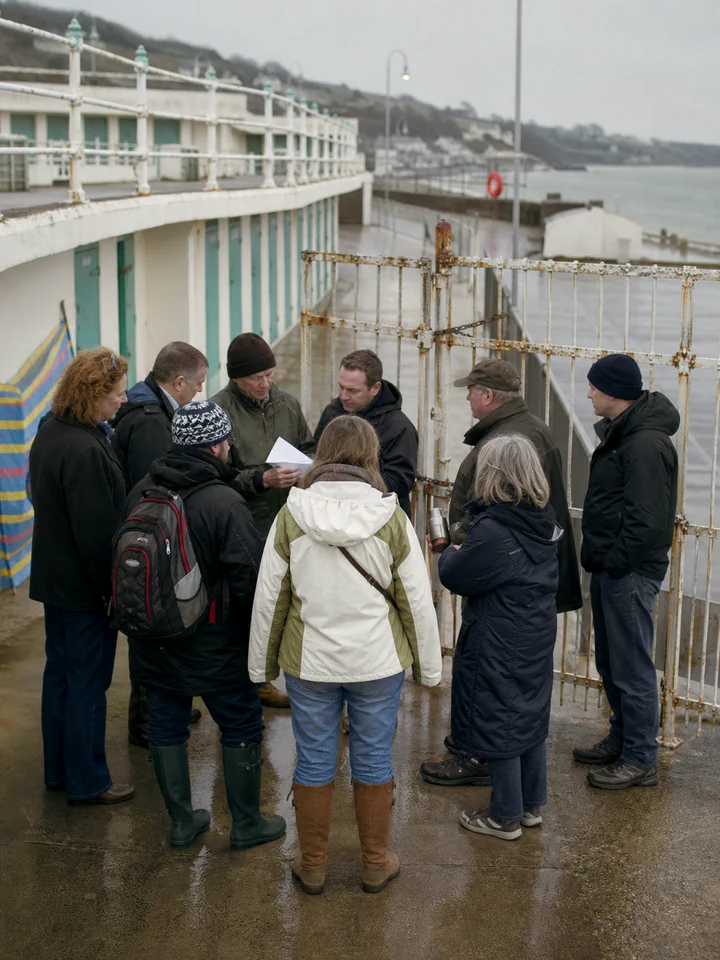 Members of the trust standing together on the unrestored poolside in winter.